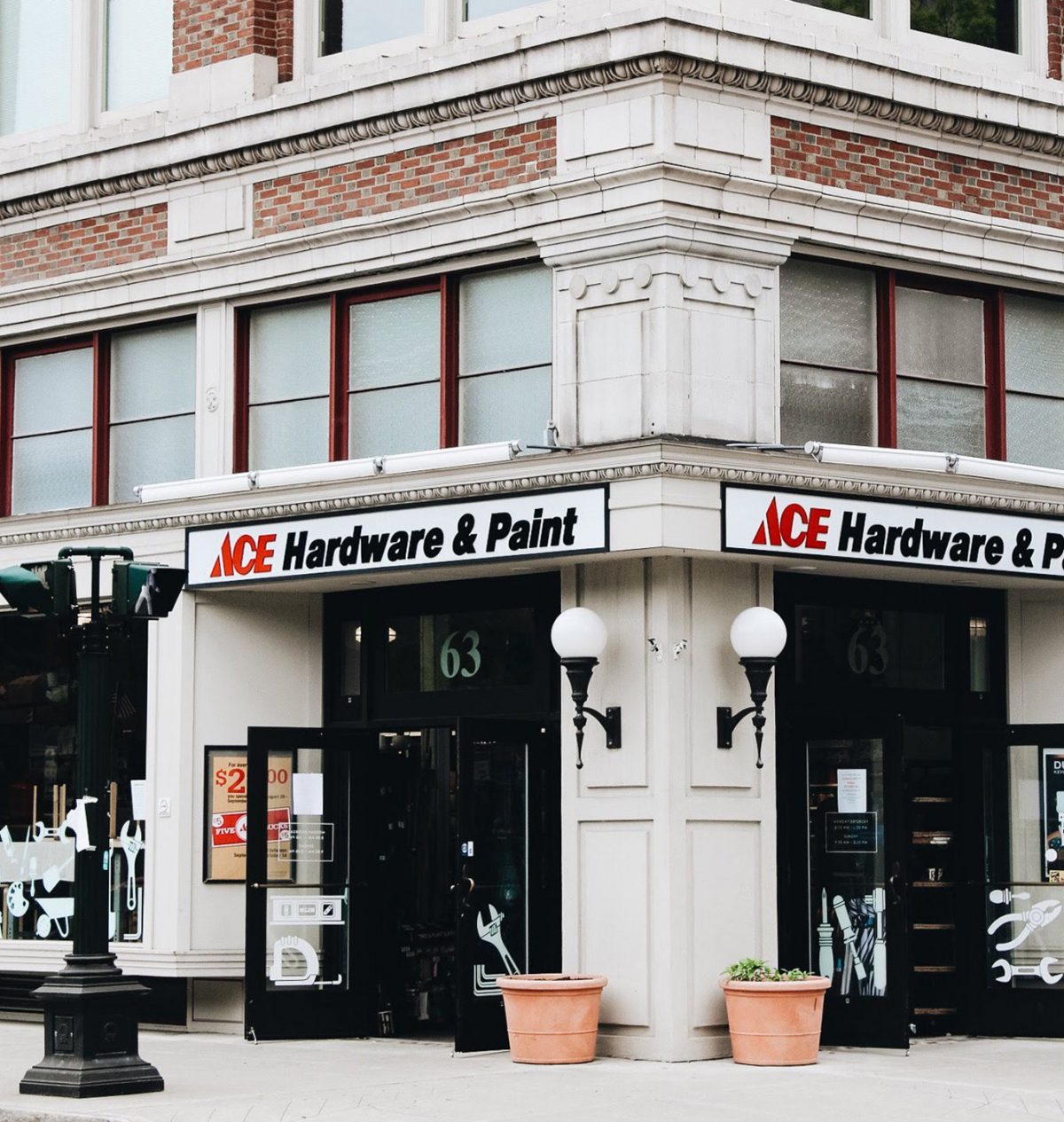 The image depicts a white building with several windows and two entrance doors. The building has a sign that reads 